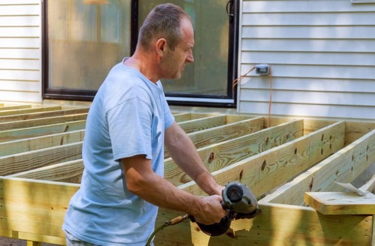 installing-of-wooden-deck-patio-carpenter-hammering-on-a-deck-patio_t20_GgYVZ6